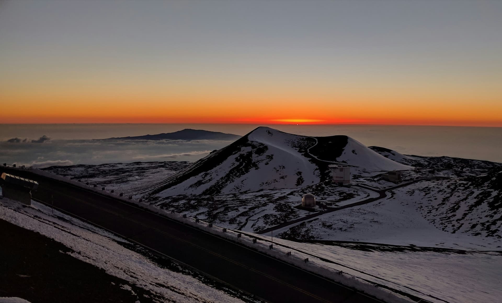 The Mauna Kea Visitor Information Station at dusk with the cloud line below